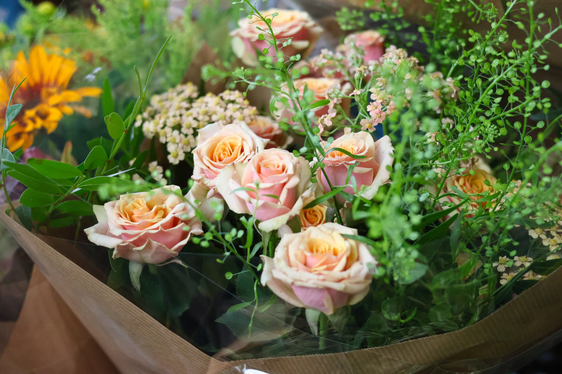 Peach roses and greenery arranged in a full bouquet